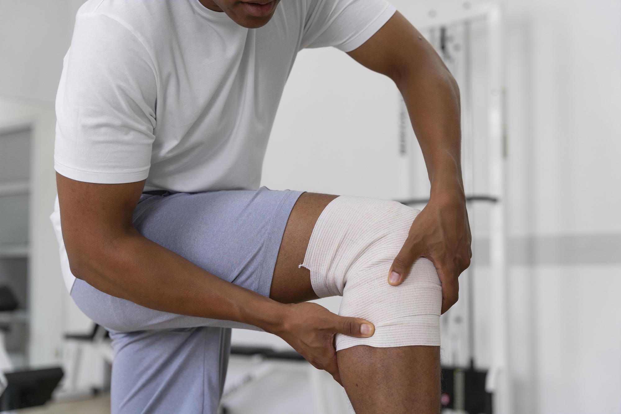 Homme avec bandage au genou - L'importance d'être accompagné par un coach sportif pour éviter les blessures en remise en forme